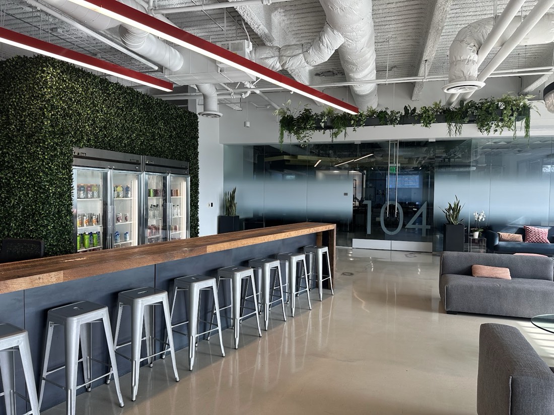 Dense hedge-style green wall installed behind an office bar in Los Angeles