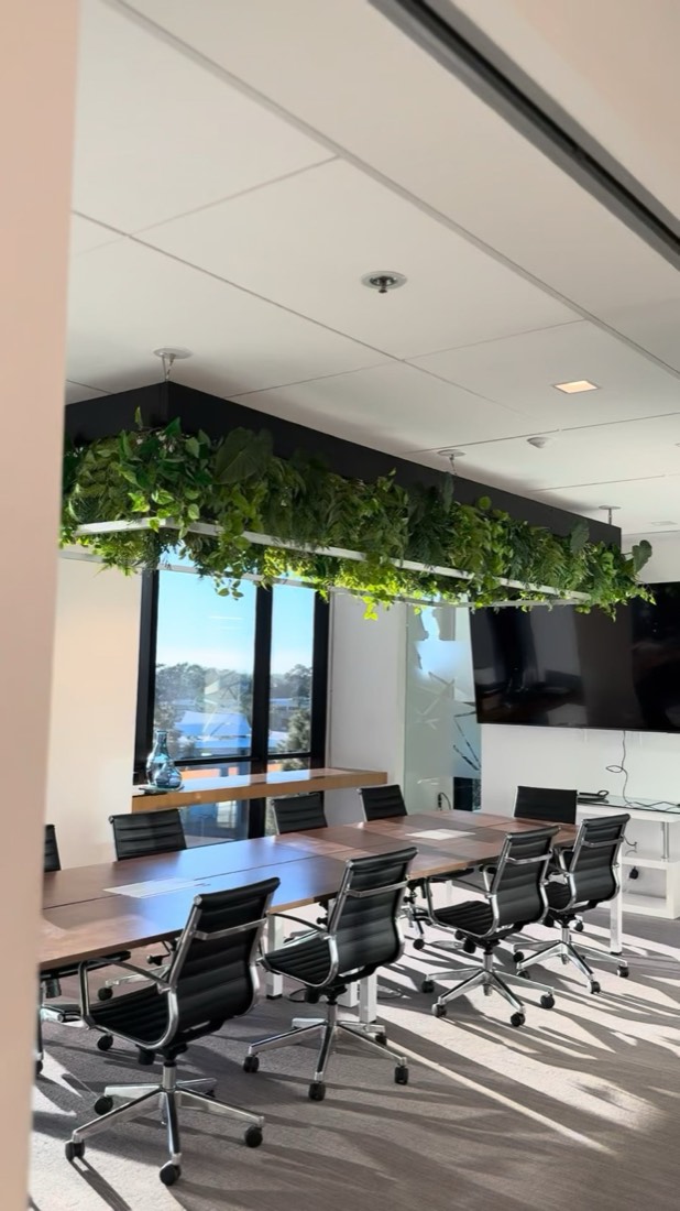 Greenery-integrated linear light fixture suspended over a conference table