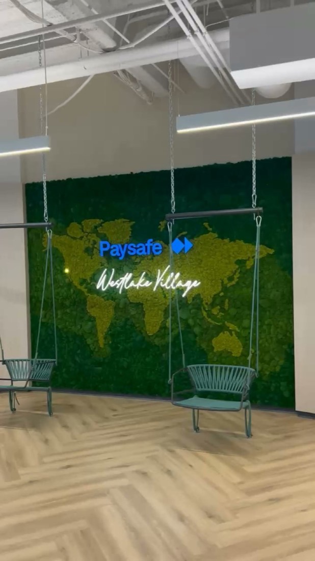 World-map moss wall with company logo and hanging chairs
