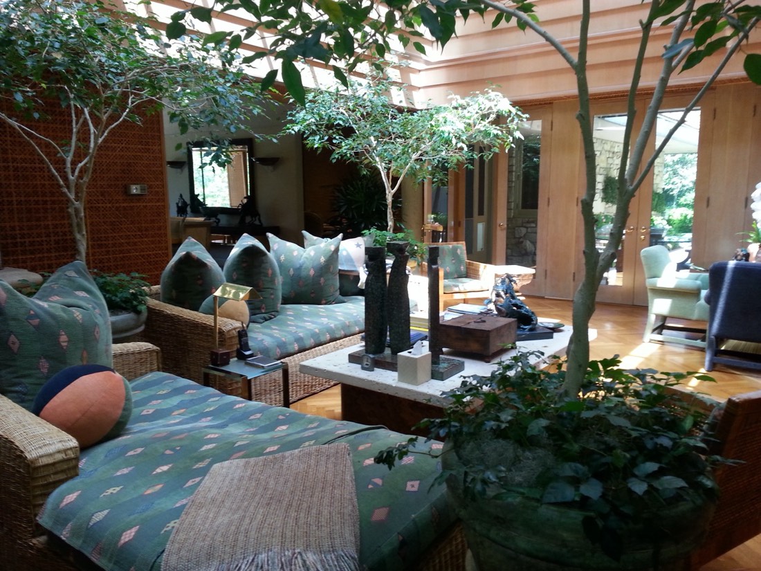 Conservatory seating area surrounded by indoor trees in a historic home