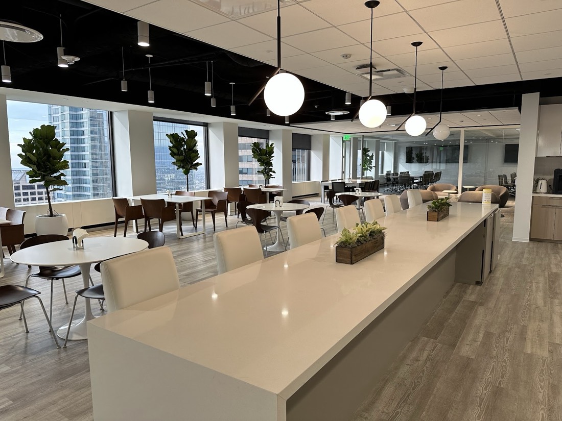 Succulent centerpiece arrangements spaced along a communal table in front of floor-to-ceiling windows with a city view