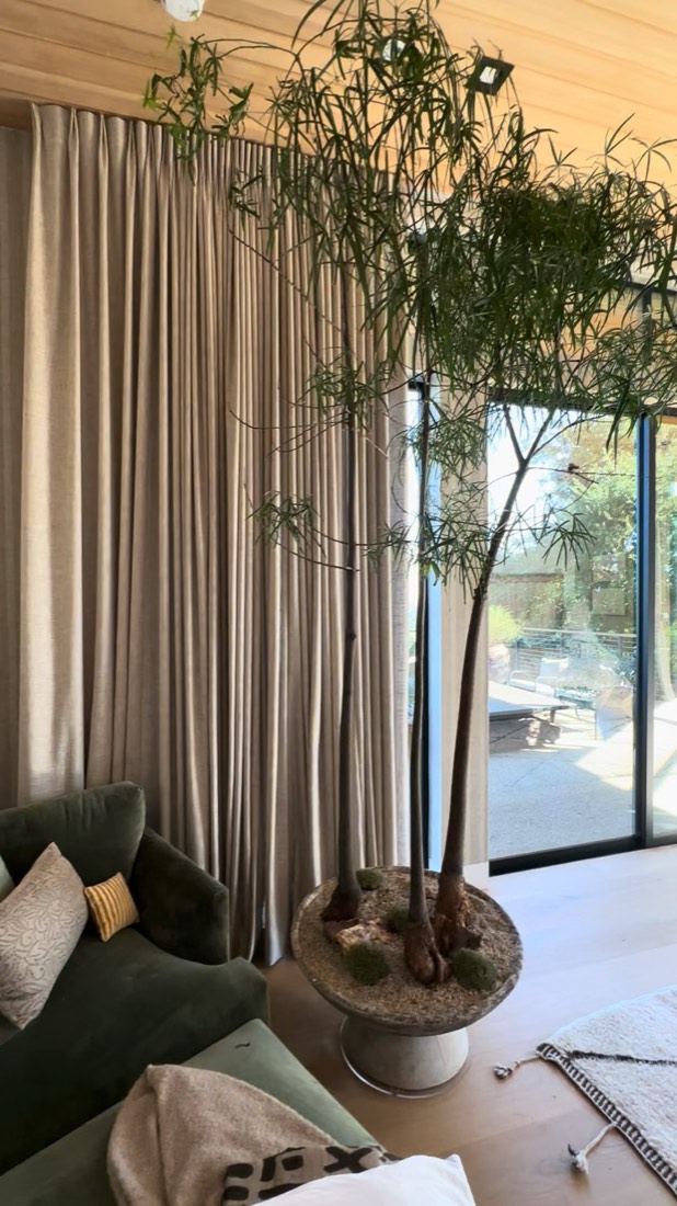 Custom faux tree by The Plant Artist standing beside a green velvet sofa